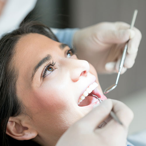 Young woman smiling with mouth open receiving general dentistry services.